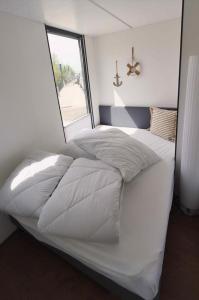 a white bed in a room with a window at Hausboot La Mare Claudia in Weyhe