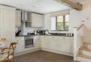 a kitchen with white cabinets and a staircase at Hampton Wafre Cottage in Leominster