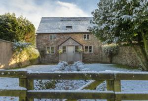 a stone house in the snow with a fence at Hampton Wafre Cottage in Leominster