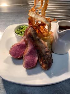 a plate of food with meat and a side of peas at Thornhill Inn in Thornhill