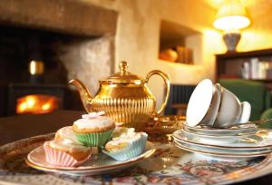 a table topped with cupcakes and a tea kettle at Scargill Castle in Barningham