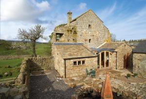 an old stone house with a stone wall at Scargill Castle in Barningham