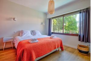 1 dormitorio con 1 cama con manta roja y ventana en Villa of the source, en Arcachon