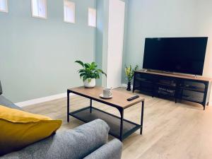 - un salon avec une télévision et une table basse dans l'établissement Le Mimosa, Maison-Jardin dans Rennes- 2 chambres, à Rennes