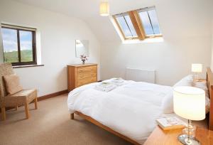 a bedroom with a large white bed and a chair at Harvest Moon in Honiton