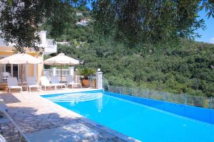 a swimming pool with chairs and umbrellas next to a house at Villa Kyriaki in Kalami