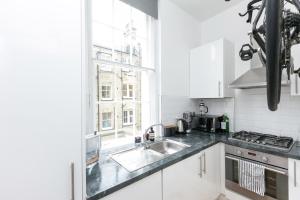 a white kitchen with a sink and a window at Light filled studio with view of Regents Park in London
