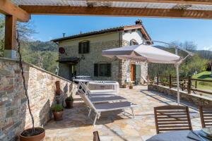 un patio con sombrilla, mesa y sillas en Villa Fenice Country House, en Borgo a Mozzano
