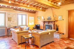 een woonkamer met rieten stoelen en een open haard bij Villa Fenice Country House in Borgo a Mozzano
