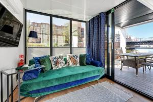 a living room with a green couch on a balcony at Domy Na Wodzie - La Mare Motlava Houseboats with Sauna by Downtown Apartments in Gdańsk