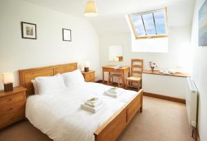a bedroom with a large white bed with towels on it at Lower Curscombe Barn in Honiton