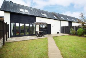 a white house with a table and an umbrella at Lower Curscombe Barn in Honiton