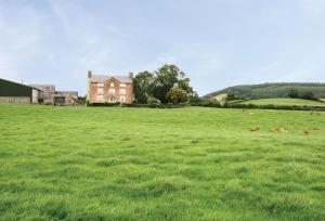 a large grassy field with a house in the background at Upper Mowley in Kington
