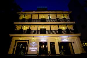 um grande edifício branco com uma varanda à noite em Le Chateau em Pondicherry