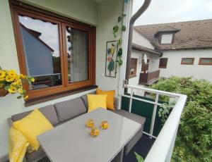 balcón con mesa y almohadas amarillas en BCA Family Apartments Herzo Süd en Herzogenaurach