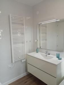 Baño blanco con lavabo y espejo en SEAFRONT APARTMENT PINEDA BEACH, en La Pineda
