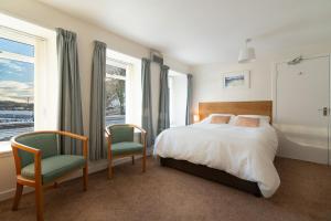 a bedroom with a bed and two chairs at Harbour Guest House in Tobermory