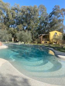 une grande piscine d'eau bleue devant une maison dans l'établissement Resort La Ghiaia, à Sarzana
