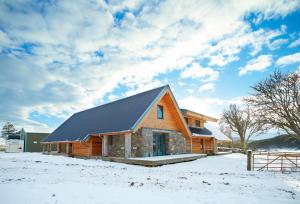 a house with a black roof in the snow at Am Bathach in Achnahanat