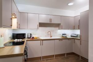 a kitchen with white cabinets and a sink at Sevenstones in Landewednack