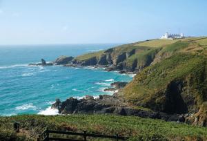 a view of the ocean with a lighthouse on a cliff at Longships in Landewednack