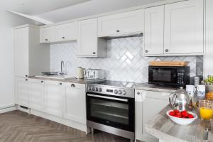 a kitchen with white cabinets and a black oven at Round Island in Landewednack