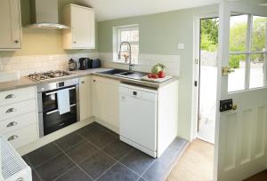 a kitchen with white cabinets and a sink at Librarian's Cottage in Coneysthorpe
