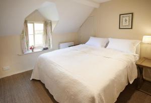 een slaapkamer met een groot wit bed en een raam bij Librarian's Cottage in Coneysthorpe
