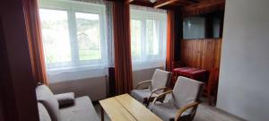 Una habitación con una mesa y sillas y ventanas. en Ružová Vila, en Banská Štiavnica