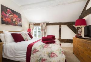 a bedroom with a bed with red pillows on it at Cobbler's Cottage in Pembridge