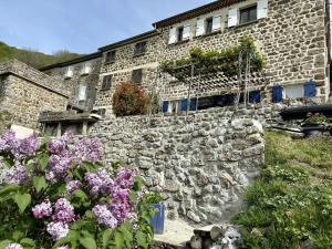a stone building with flowers in front of it at Gîte de NOE au Ray-pic in Péreyres