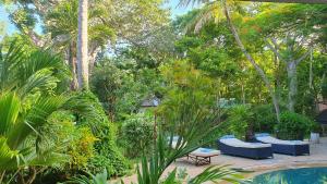 a garden with a pool and palm trees and blue chairs at Mami Wata House in Kwale
