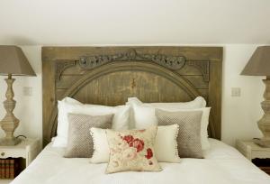 a bed with a large wooden headboard and pillows at Rectory Cottage in Stamford