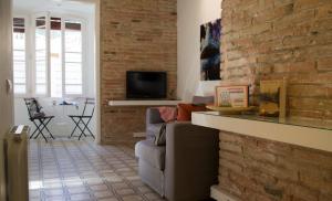 - un salon avec un mur en briques et un canapé dans l'établissement Happy People Gaudi Sant Pau Apartments, à Barcelone
