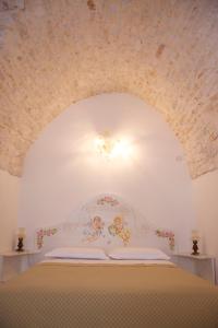 Schlafzimmer mit einem weißen Bett und einer Decke in der Unterkunft Casa del Carbonaio in Locorotondo