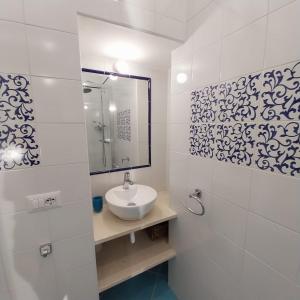 a white bathroom with a sink and a mirror at La Casa Di Massimiliano - Villa del Sole in Capri