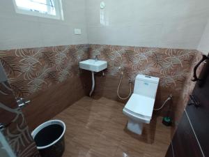 La salle de bains est pourvue de toilettes et d'un lavabo. dans l'établissement Karpagam Residency, à Ooty