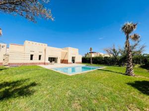 een villa met een zwembad en een palmboom bij VILLA Halima in Marrakesh