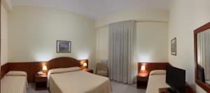 a hotel room with a bed and a tv at Il Nocchiero City Hotel in Soverato Marina