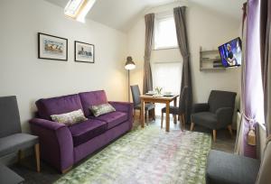 Mason's Cottage في Ampleforth: غرفة معيشة مع أريكة أرجوانية وطاولة