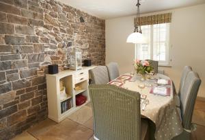 een eetkamer met een tafel en stoelen en een bakstenen muur bij Courtyard House in Kelso