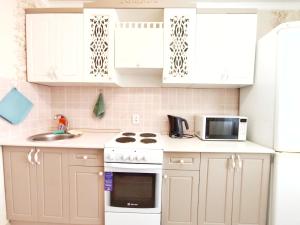 cocina con armarios blancos, fregadero y microondas en Люксовые апартаменты в Центре г.Семей, en Semey
