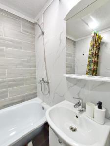 La salle de bains blanche est pourvue d'un lavabo et d'une baignoire. dans l'établissement Люксовые апартаменты в Центре г.Семей, à Semey