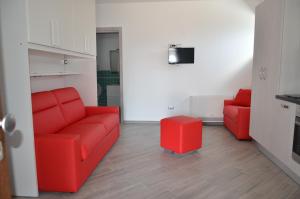 a living room with a red couch and a stool at La Rosa Dei Venti in Acciaroli
