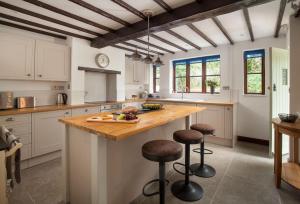 a kitchen with white cabinets and a wooden island with bar stools at Smithycroft in Combe Saint Nicholas