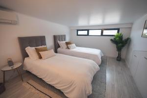 a bedroom with two beds and a potted plant at Ribeira Grande Ocean View Apartment in Ribeira Grande