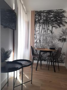 - une table et des chaises dans une pièce ornée d'une fresque murale de palmiers dans l'établissement VuT. El Balcón de la Plaza - B., à Ciudad-Rodrigo