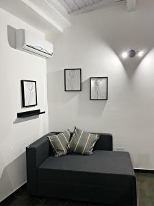 ein schwarzes Sofa in einem Zimmer mit drei Bildern an der Wand in der Unterkunft La casa di Eva in Avola