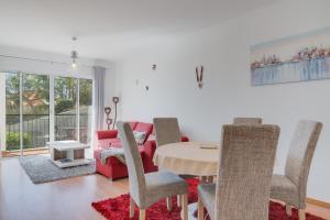 Una sala de estar con una mesa y un sofá rojo. en Alta do Garajau II, en Caniço