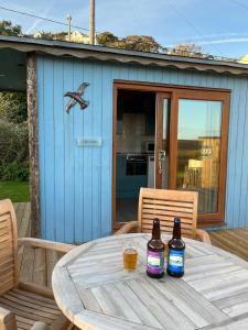a table with two bottles of beer on a patio at Cove Shepherds Hut in Penally